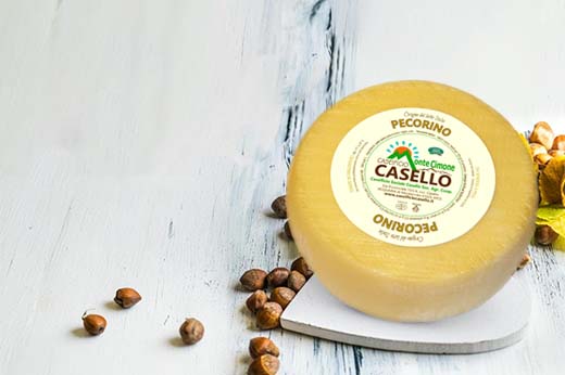 pecorino su un tagliere a forma di cuore con della frutta secca sparsa sul ripiano