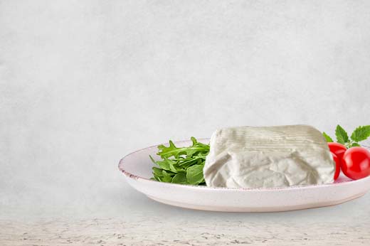 stracchino del caseificio casello in un piatto con un ciuffo di rucola a sinistra e dei pomodorini a destra
